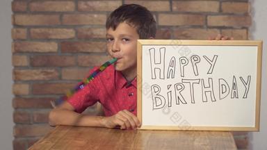 孩子坐着桌子上持有<strong>白板</strong>纸上的内容刻字快乐生日背景红色的砖墙